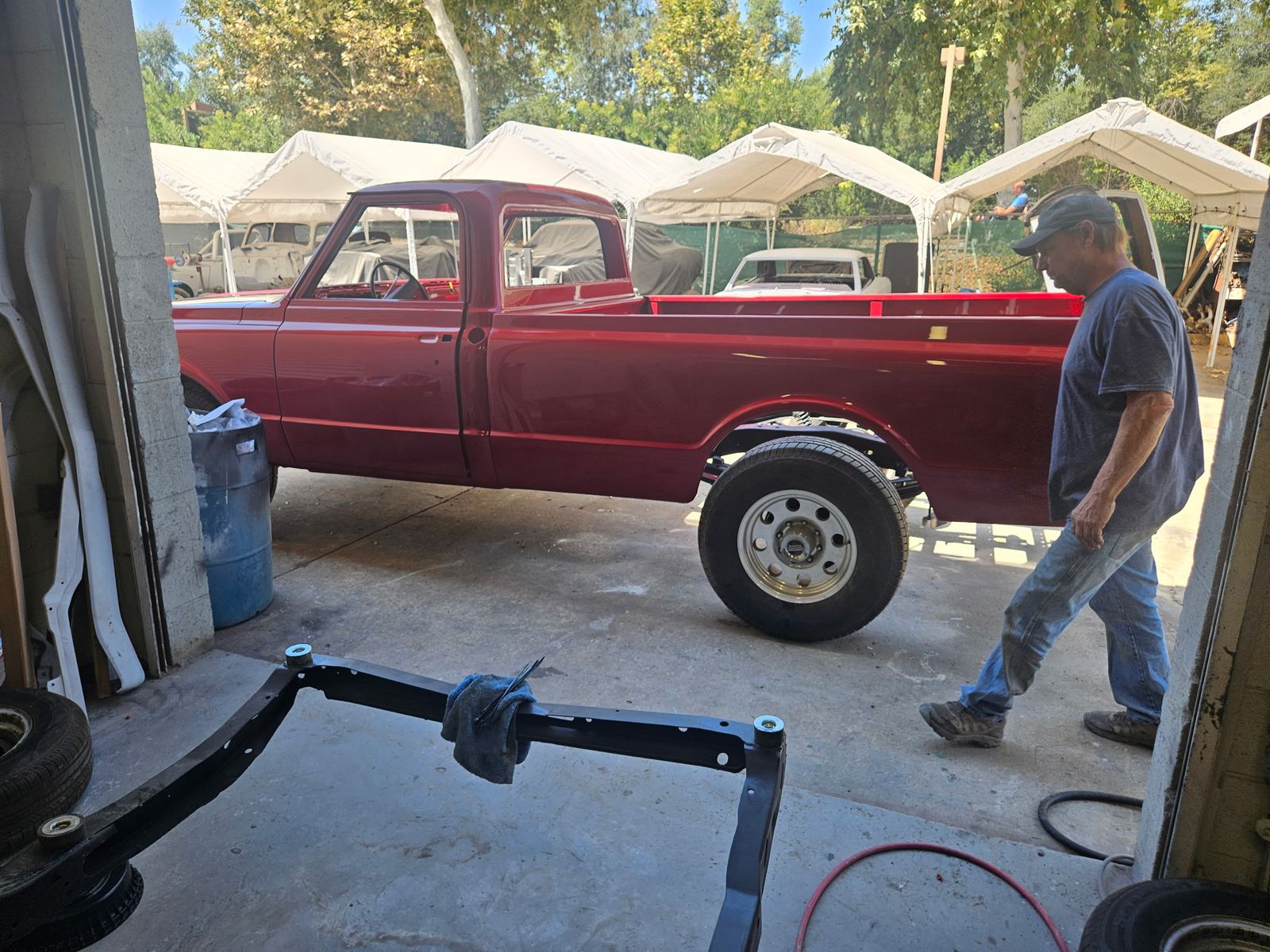 1969 Chevrolet C10 — Mid-assembly at the shop door, front clip still off.