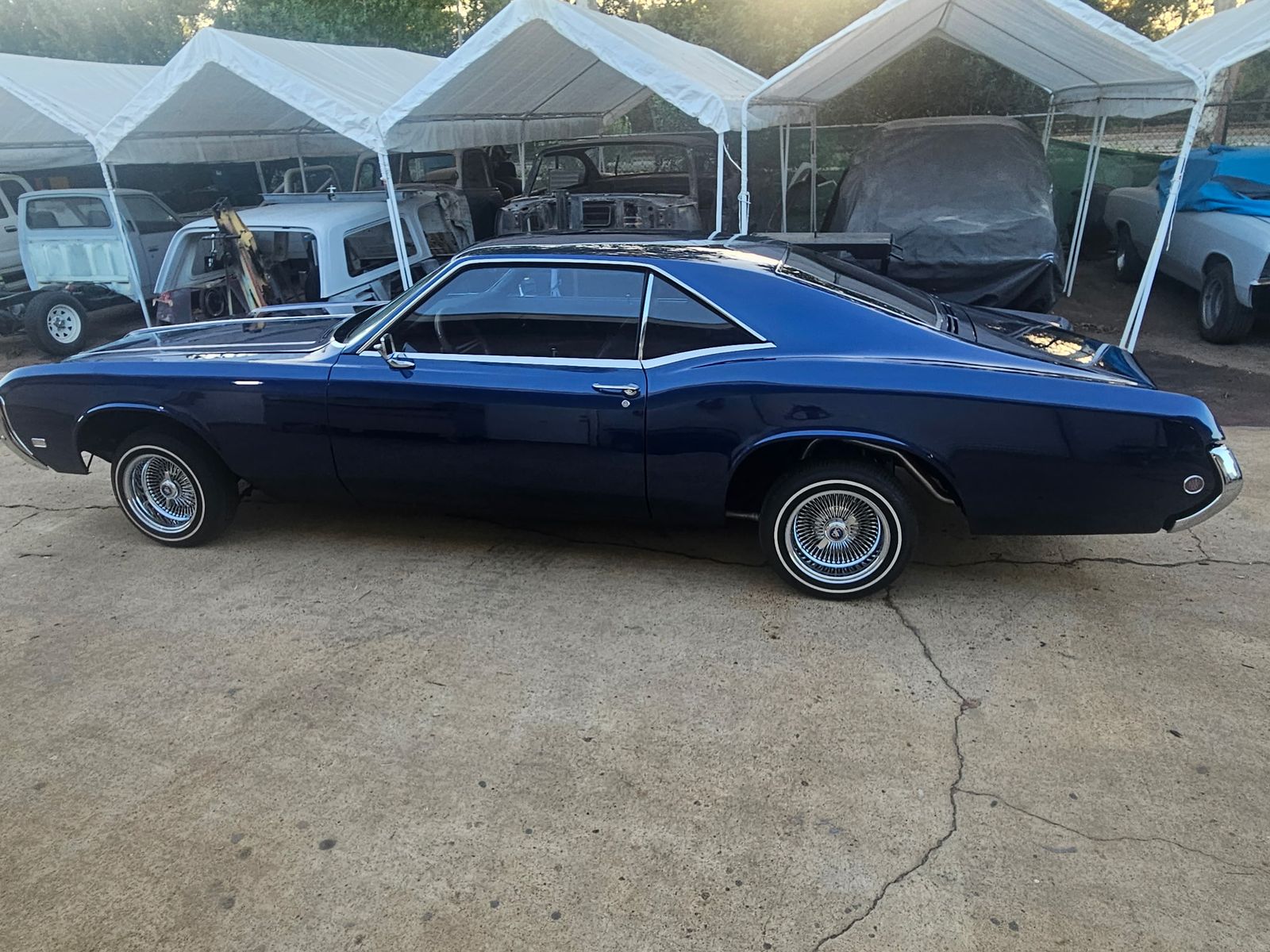 Restored Buick Riviera in deep midnight blue, side profile outside the Santee shop
