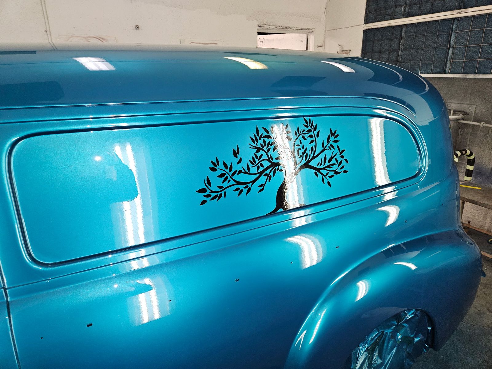 1941 Chevrolet Sedan Delivery — The mural panel under shop light — metal leaf trunk against candy teal.